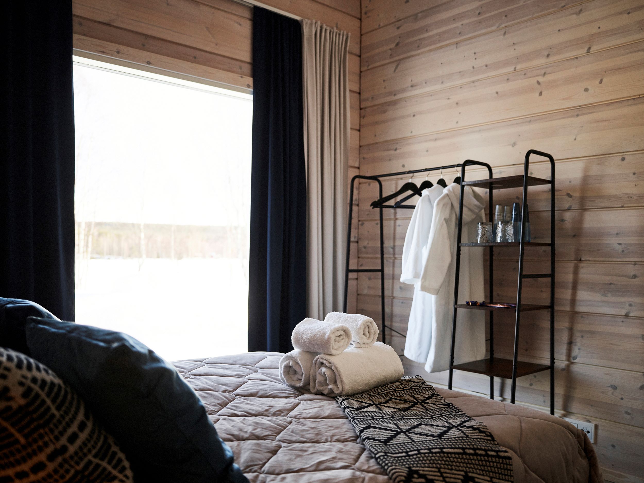 An accommodation room with a bed and window size of the whole wall. Lapland Luxury Hideaways