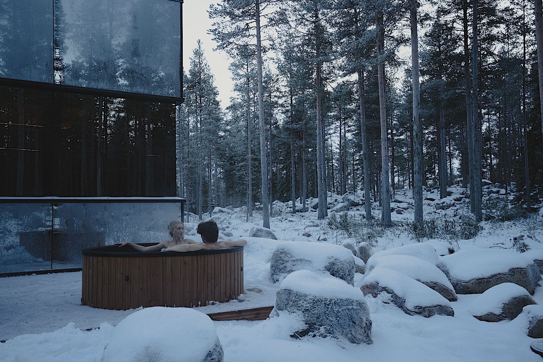 Kaksi ihmistä ulkona paljussa talvella, Invisible Forest Lodge, Rovaniemi