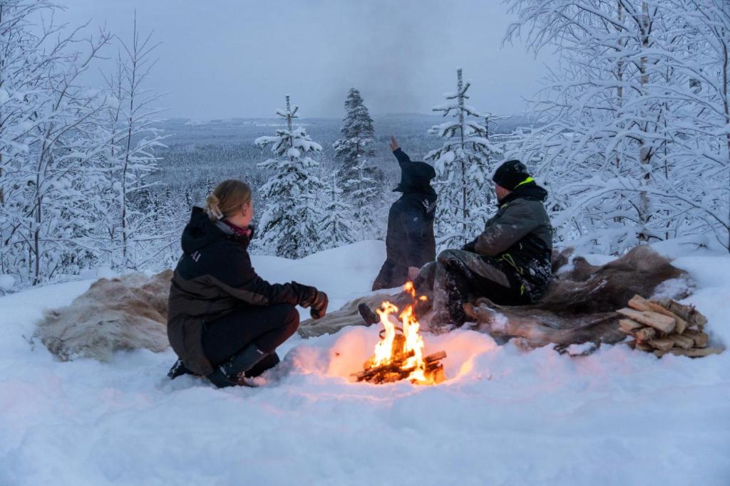 People around a open fire in a snowy forest in Rovaniemi, Lapland, Finland, Tour by Kotatuli Experience