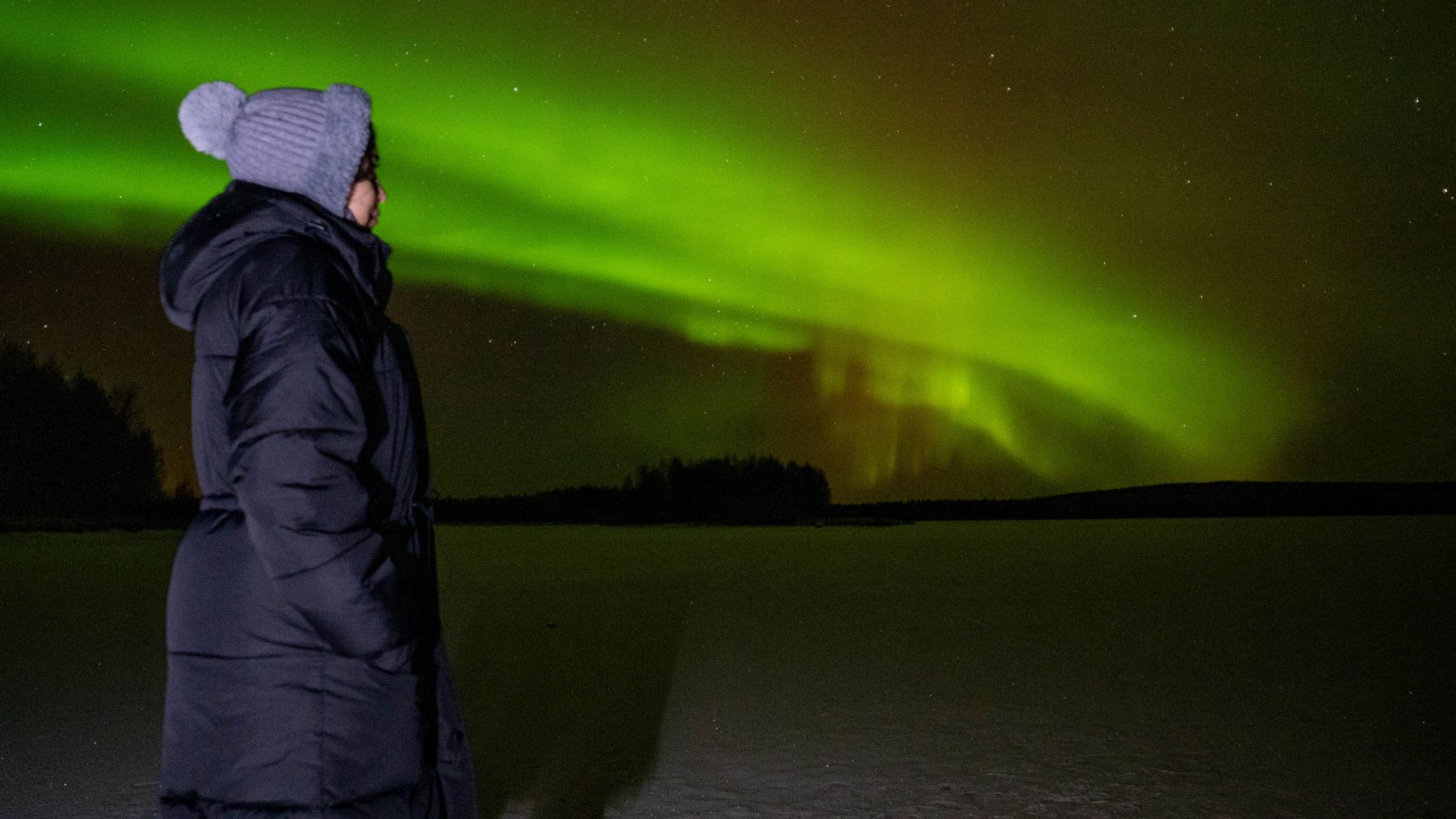 Person looking at green northern lights in the sky, Rovaniemi, Lapland, Finland