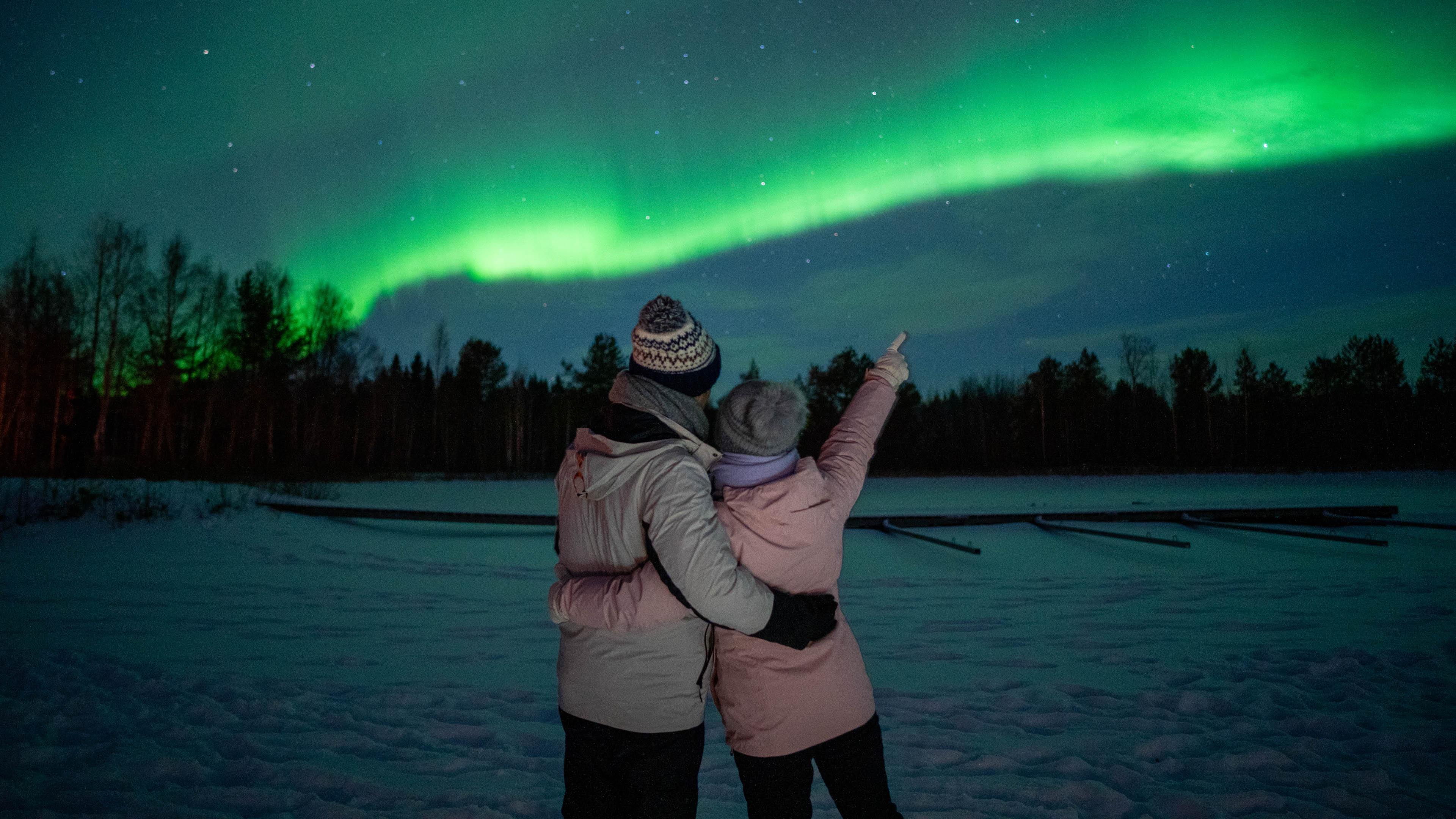 Couple watching northern lights in the sky, Rovaniemi, Lapland, Finland