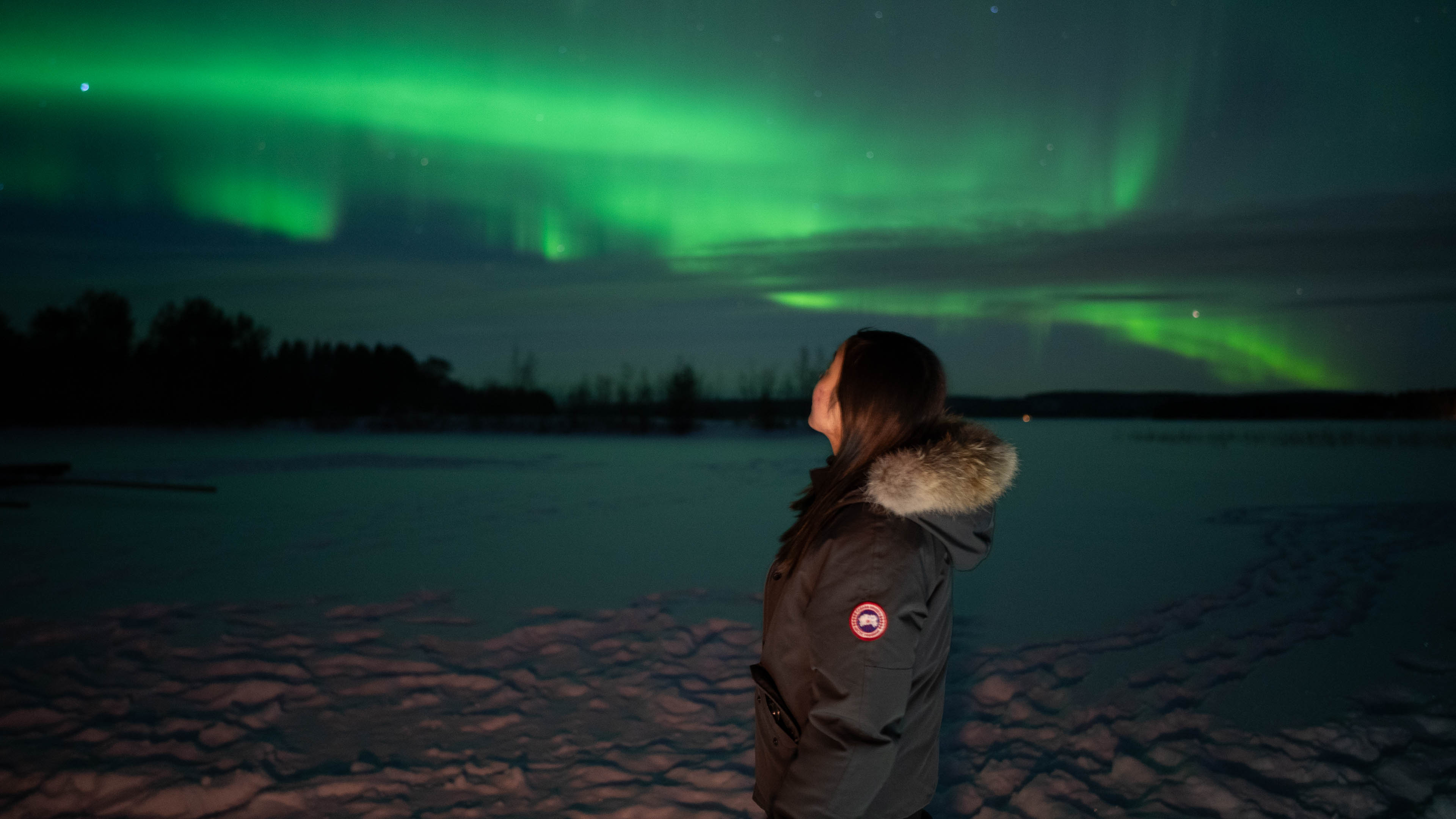 Woman looking at the green northern lights in the sky in Rovaniemi, Lapland, Finland