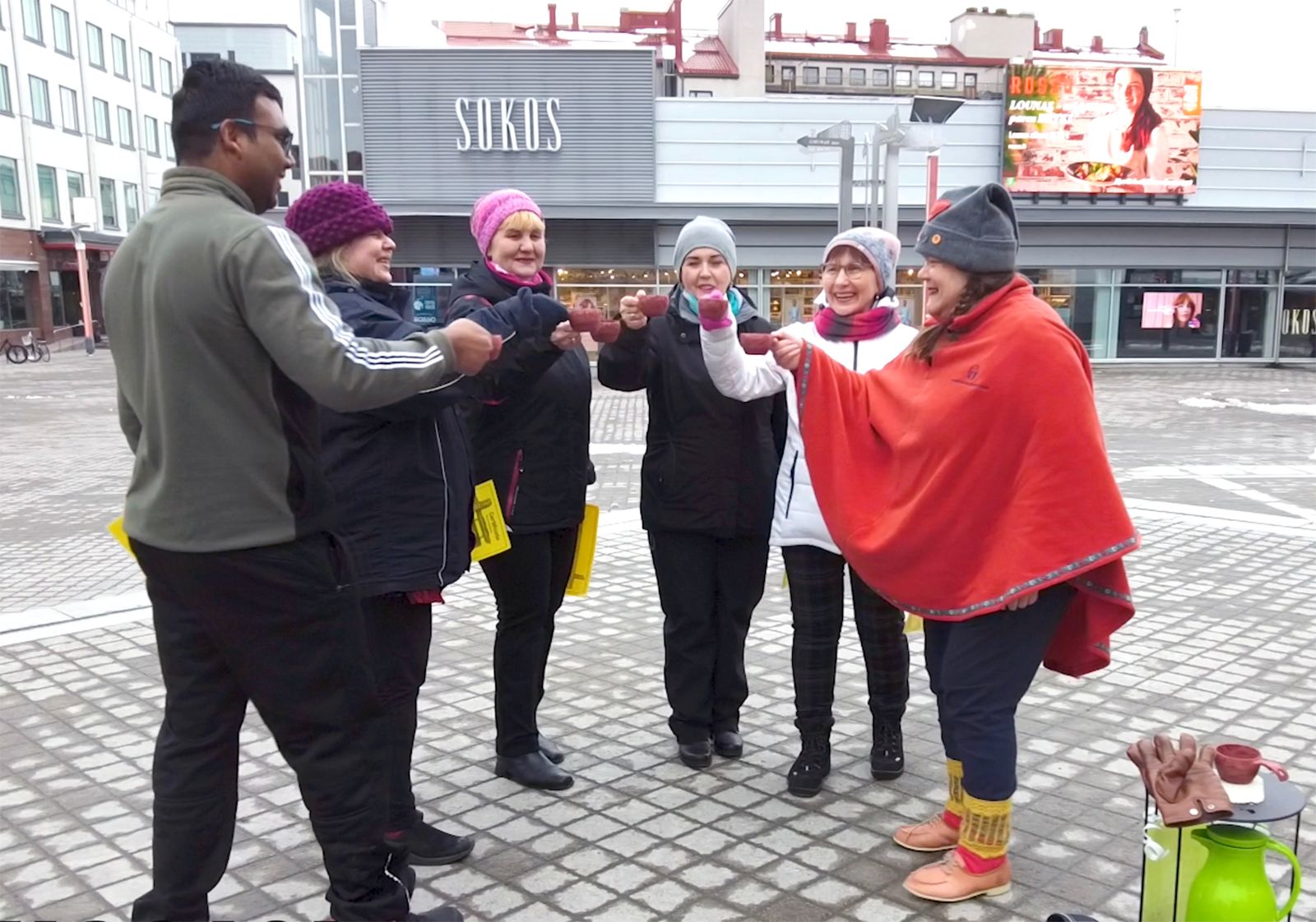 group having a celebration toast at Lordi's Square with Rovaniemi Wellness Tours