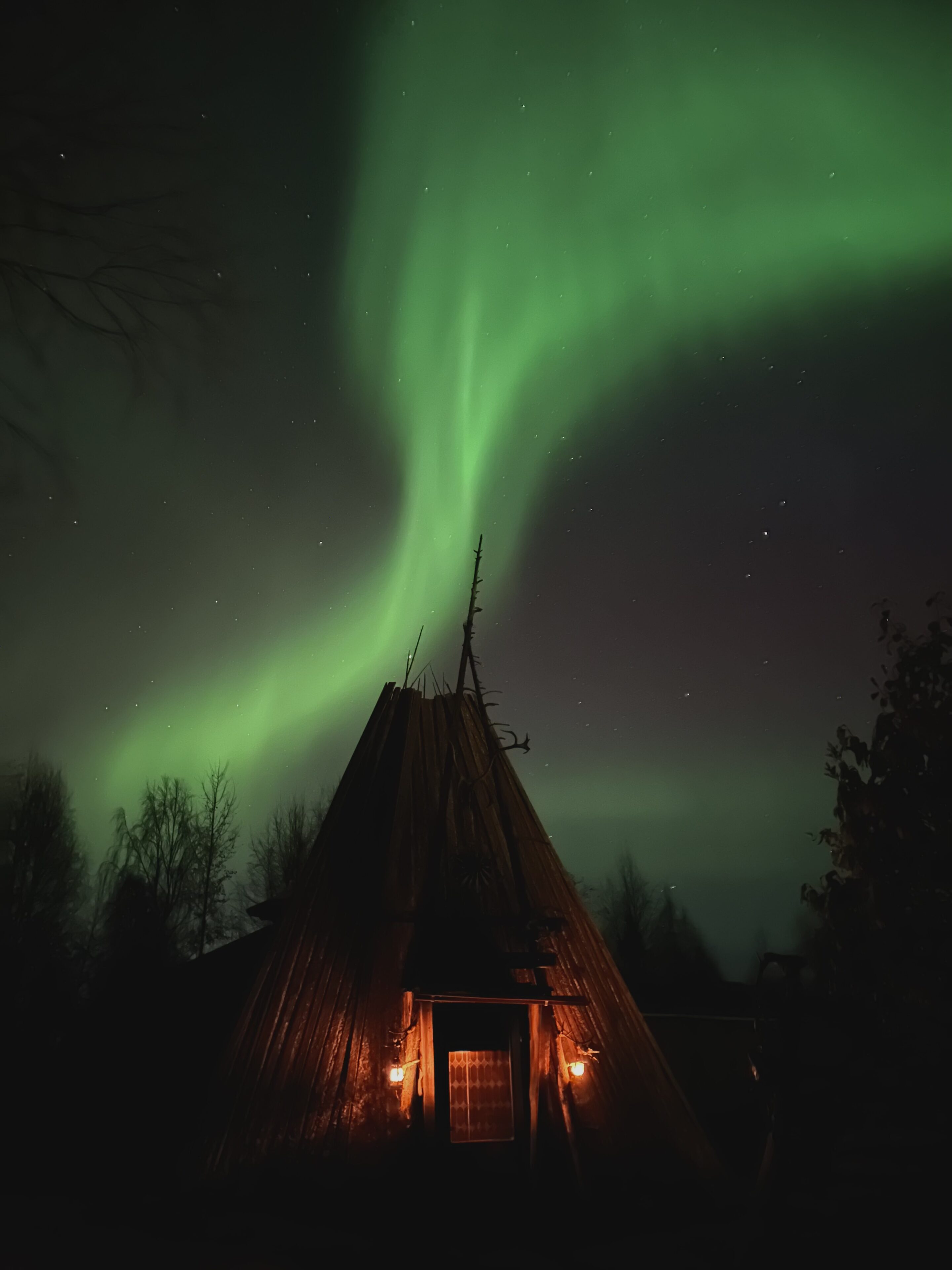 Lean-to shelter Kota in Shaman Village, northern lights in the sky in Rovaniemi, Lapland, Finland