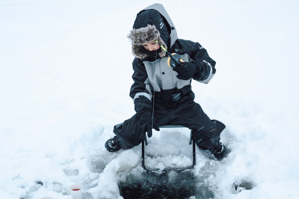 child is doing ice fishing in winter